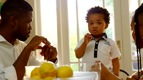 Front-view-of-young-black-family-having-food-at-dining-table-in-kitchen-of-comfortable-home-4k