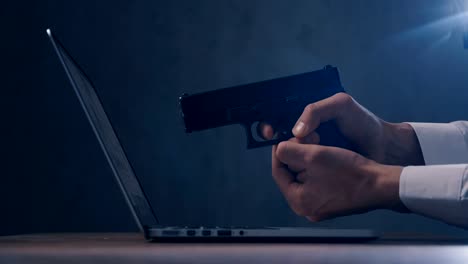 Male-hand-aims-the-gun-at-the-computer-screen.-Concept-of-cyber-robbery.
