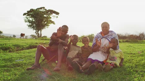 Family-sitting-on-the-grass-and-waving-hands