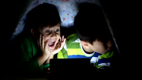 Little-boy-reading-book-on-digital-tablet-at-night