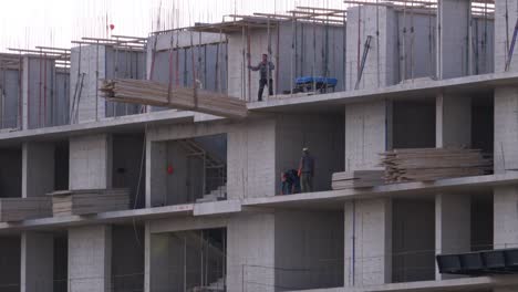 Constructores-en-un-sitio-de-construcción.-La-grúa-en-un-sitio-de-construcción-levanta-una-carga.-Construcción-de-edificios