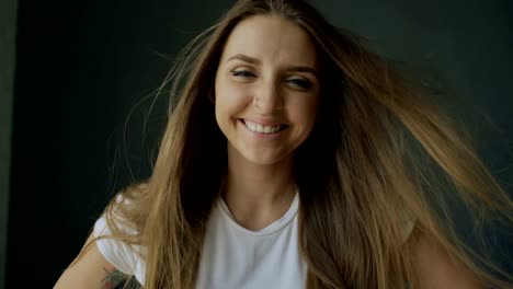 Portrait-of-young-smiling-woman-with-hair-flying-of-wind