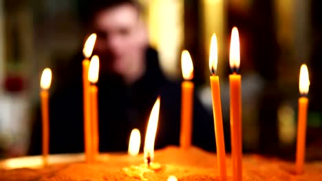 A-man-from-afar-looks-at-candles-burning-in-a-candlestick-in-a-Christian-Church