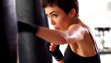 Atractivo-Boxer-femenino-entrenamiento-perforando-un-saco-en-el-gimnasio