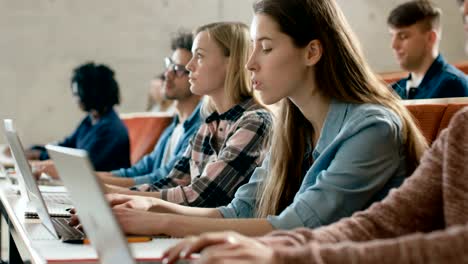 Zeile-der-Multi-ethnischen-Studenten-arbeiten-auf-den-Laptops-beim-hören-einen-Vortrag-im-modernen-Unterricht.-Helle-Jugendliche-Studie-an-der-Universität.