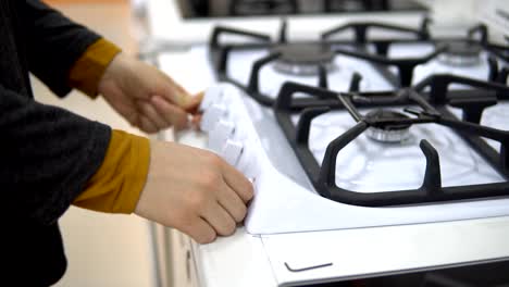 Una-mujer-joven-elige-una-estufa-de-gas-en-una-tienda-de-electrodomésticos-para-el-hogar.