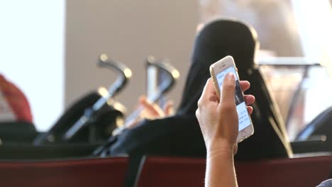 Unrecognizable-man-uses-a-smartphone-in-airport-waiting-lounge.-Guy-expectations-of-flight-at-terminal.-Rear-back-view-Close-up