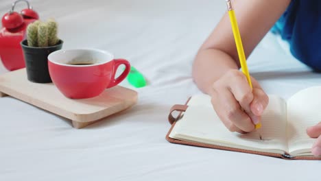 Woman-hands-with-pen-writing-notebook-on-bedroom.4k-Footage-with-dolly-shot