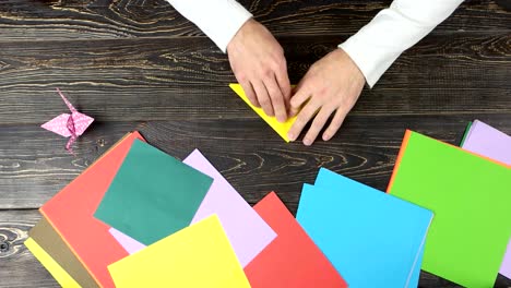 Male-hands-folding-yellow-paper-sheet.