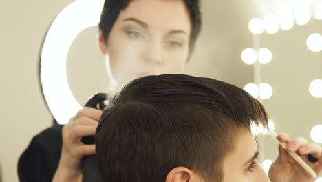 Woman-hairdresser-combing-male-hair-with-comb-and-sprinkling-water-before-haircuting-in-beauty-salon.-Hair-stylist-working-in-hairdressing-salon