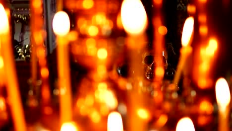 Skull-in-focus,-in-the-foreground-burning-candles-in-the-Christian-Orthodox-Church