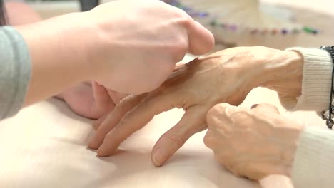 Manicurist-filing-nails-to-senior-woman.