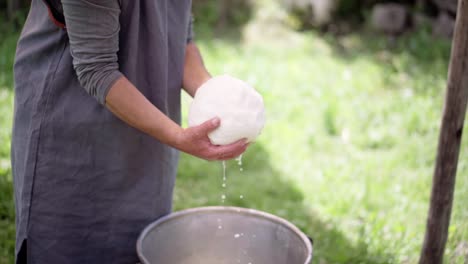 Making-cheese-from-sheep's-milk-manually.-Frothed-milk-timber-pressure-in-a-metal-barrel-making-cheese-from-sheep's-milk-manually-ancient-Italian-tradition.-Cheese-production