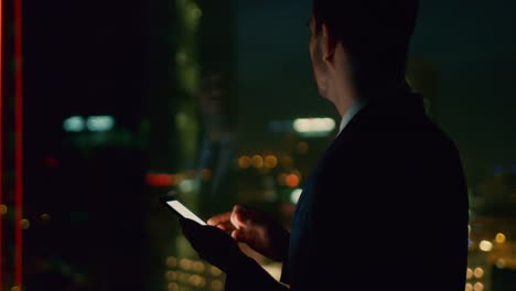 Spät-abends-im-Büro-Typen-erfolgreicher-Geschäftsmann-E-Mail-auf-das-Smartphone.-In-der-Ansicht-Fenster-Geschäftsviertel-mit-Citylights.