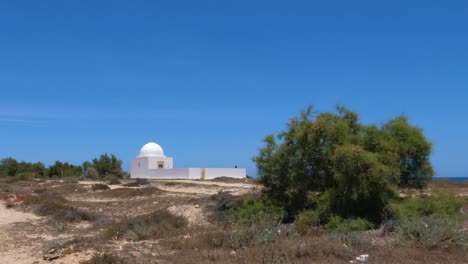 Lonely-white-stone-chapel-at-sea-island-on-blue-sky-background