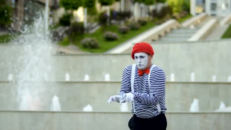 Lustige-Mime-in-roten-Baskenmütze-Klavierspiel-im-Brunnen-Hintergrund