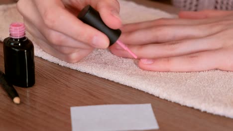 Mujer-pone-primera-capa-de-laca-color-rosa-en-sus-uñas.-Close-up.