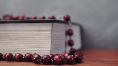 Biblia-y-el-crucifijo-granos-sobre-una-mesa-de-madera-rojo-Fondo-hermoso.-Concepto-de-religión-cerca-de-upBible-y-los-granos-de-crucifijo-en-una-mesa-de-madera-roja.-Fondo-hermoso.-Concepto-de-la-religión-de-cerca