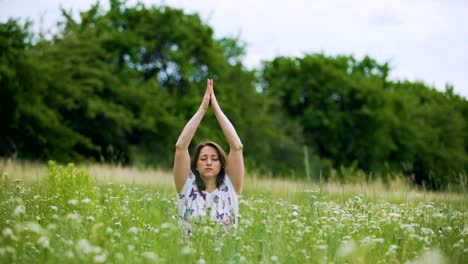 Mujer-joven-en-hierba-verde-haciendo-práctica-budista,-namaste-después-de-la-meditación