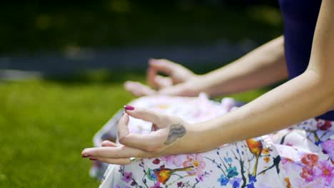 Hands-in-gyan-mudra-rack-focus,-woman-sits-in-park-and-meditates,-proper-pose