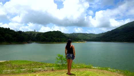 A-girl-is-standing-alone-on-the-edge-looking-straight-at-the-lake-with-mountains