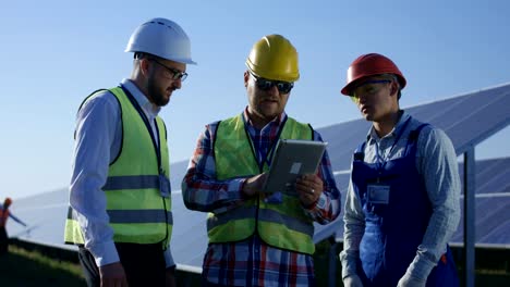 Drei-elektrische-Arbeiter-überprüfen-von-Dokumenten-auf-einem-tablet