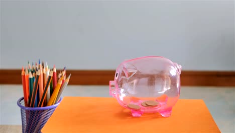 Hand-of-boy-putting-coin-into-piggy-bank.-Saving-for-education-fund-concept