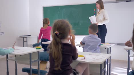 Kinder-in-der-Schule,-Kinder-erziehen-ihre-Hände-um-Lehrer-Frage-zu-beantworten,-Schulmädchen-geht-zur-Tafel,-einfaches-Beispiel-zu-schreiben