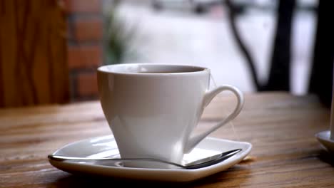 White-Cup-of-Hot-Tea-on-the-Table-in-a-Cafe-on-the-Background-of-the-Street-Window