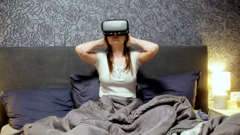 Beautiful-young-woman-wearing-VR-Headset-on-the-bed.-Looking-around,-smile-and-using-gestures-with-hands.