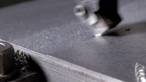 milling-machine-is-taking-off-top-level-of-metal-part-in-metalworking-shop-of-factory,-close-up-view