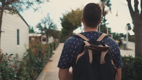 Alone-man-is-walking-on-pedestrian-road-between-bushes-in-suburban-area-in-day