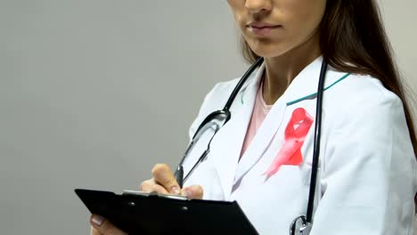 Physician-with-pink-ribbon-prescribing-treatment,-fight-against-breast-cancer