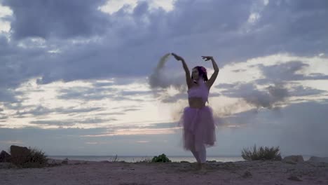 Joven-tierna-con-el-maquillaje-de-brillo-en-un-vestido-rosado-bailando-con-bombas-de-humo-al-aire-libre.-El-baile-de-una-chica-sensual-con-un-peinado-maravilloso-con-flores.-Cámara-lenta.