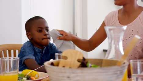 Front-view-of-mid-adult-black-father-wiping-sons-mouth-at-dining-table-in-a-comfortable-home-4k