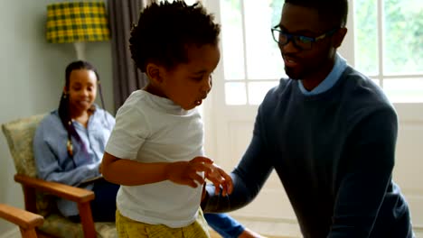 Front-view-of-young-black-father-playing-with-his-son-in-living-of-comfortable-home-4k