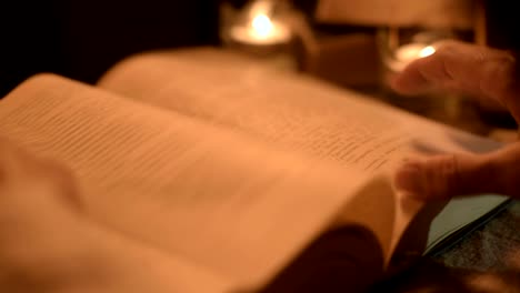 Big-Close-up-girl-magician-in-a-dark-room-with-candlelight-looking-for-a-spell-in-a-book.-Low-key-live-camera.