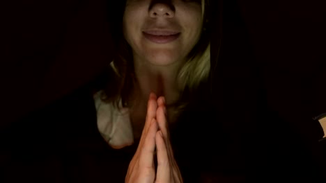 Close-up-bottom-of-the-face-of-the-girl-magician-in-a-dark-room-with-candlelight-smiling-from-the-flash-below.-Low-key-live-camera