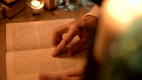 Big-Close-up-girl-magician-in-a-dark-room-with-candlelight-looking-for-a-spell-in-a-book.-Low-key-live-camera.