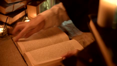 Big-Close-up-girl-magician-in-a-dark-room-with-candlelight-looking-for-a-spell-in-a-book.-Low-key-live-camera.