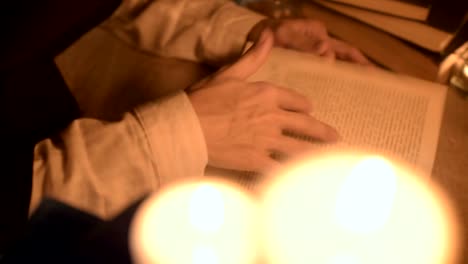 Big-Close-up-girl-magician-in-a-dark-room-with-candlelight-looking-for-a-spell-in-a-book.-Low-key-live-camera.