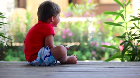 Junge-sitzt-auf-der-Veranda-und-spielt-mit-Handy