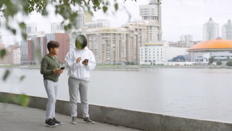 Madre-asiática-e-hijo-usando-Smartphone-y-corriendo-al-aire-libre