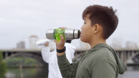 Asian-Boy-Drinking-Water-nach-dem-Laufen-mit-Mutter