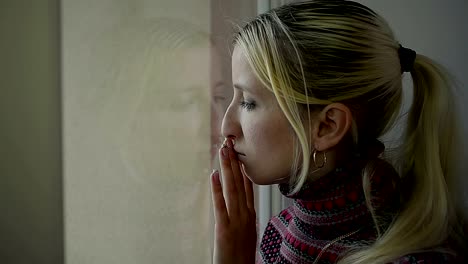 Estrecha-hasta-frustrado-joven-chica-mirando-por-la-ventana-en-casa