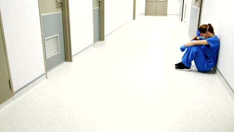 Tensed-female-doctor-sitting-in-corridor