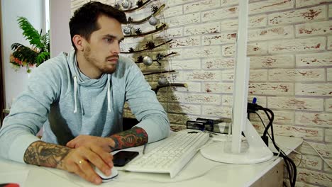 Young-bearded-businessman-in-grey-sweatshirt-working-in-bright-office.