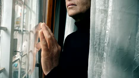 Close-up-on-hand-of-mature-woman-leaning-against-window