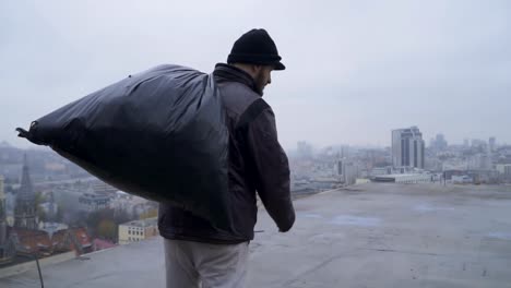 Homeless-with-garbage-bag-walks-at-the-roof-of-abandoned-building