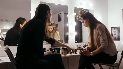 Woman-actress-with-hair-curlers-on-head-discussing-cosmetics-with-makeup-artist